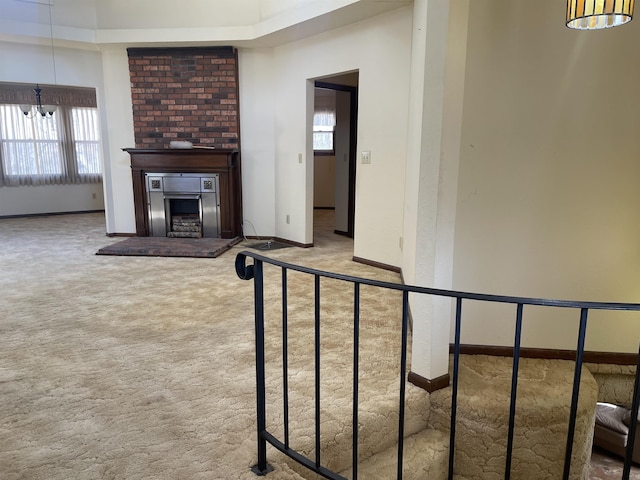 unfurnished living room featuring a large fireplace, carpet, and a notable chandelier