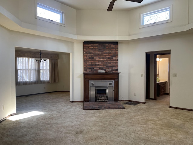 unfurnished living room featuring light carpet, a high ceiling, and ceiling fan with notable chandelier