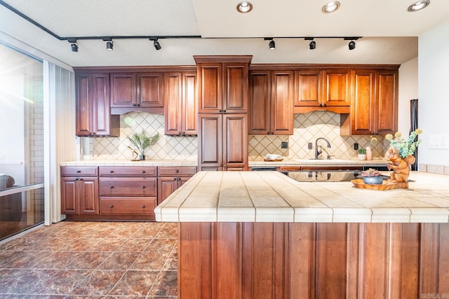 kitchen with kitchen peninsula, tasteful backsplash, tile counters, and sink