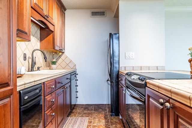 kitchen featuring black refrigerator, tasteful backsplash, electric range oven, sink, and tile counters