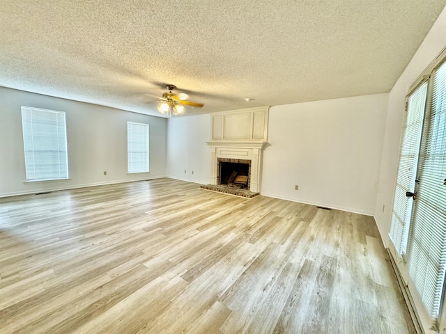 unfurnished living room with a textured ceiling, a large fireplace, plenty of natural light, and ceiling fan