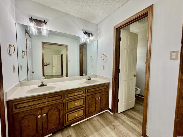 bathroom featuring hardwood / wood-style floors, vanity, toilet, and a textured ceiling