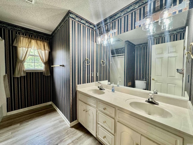 bathroom featuring hardwood / wood-style floors, vanity, toilet, and a textured ceiling