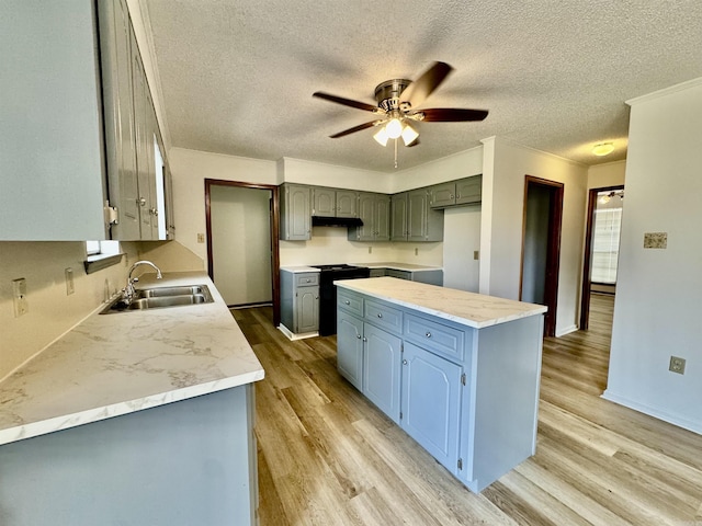 kitchen featuring ceiling fan, sink, light hardwood / wood-style flooring, stove, and a textured ceiling