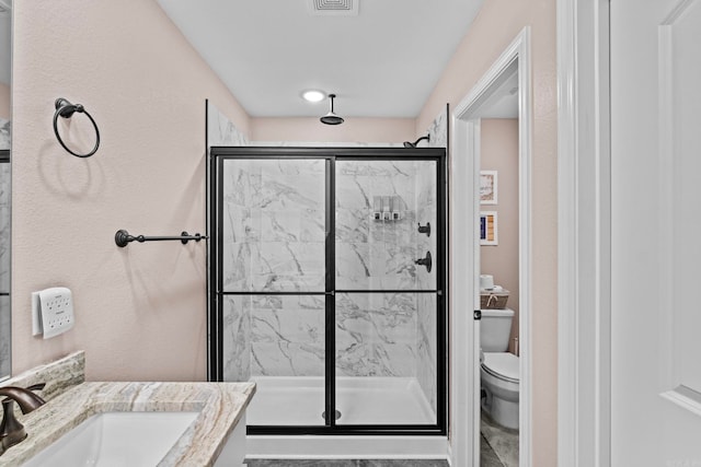 bathroom with vanity, a shower with shower door, and toilet