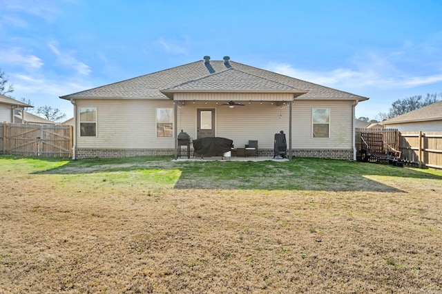 rear view of house featuring ceiling fan, a patio area, and a lawn