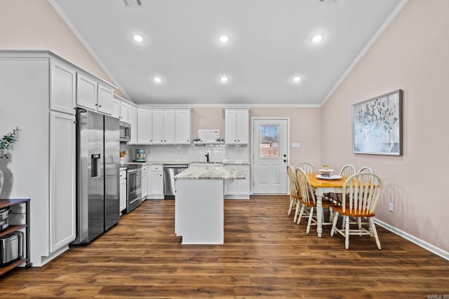 kitchen with white cabinets, crown molding, dark hardwood / wood-style floors, appliances with stainless steel finishes, and a kitchen island