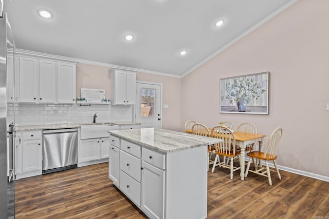 kitchen with stainless steel dishwasher, a kitchen island, white cabinets, and sink