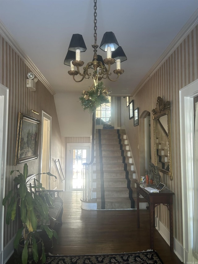 staircase featuring a notable chandelier, wood-type flooring, and ornamental molding