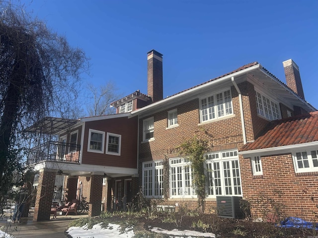 rear view of property with a balcony, a patio area, and central air condition unit