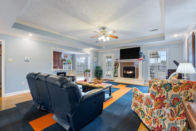 living room featuring a tray ceiling, ceiling fan, and ornamental molding