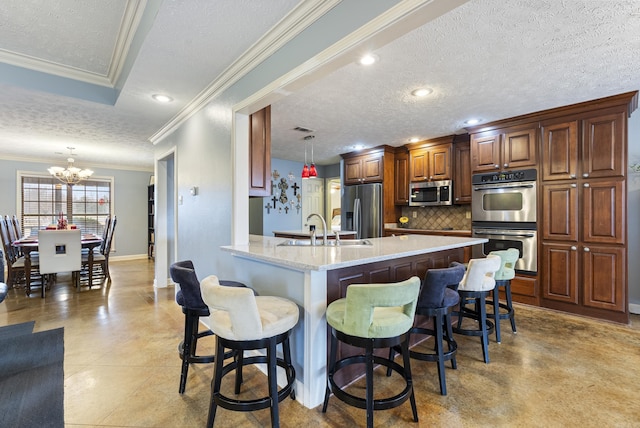 kitchen with sink, stainless steel appliances, a notable chandelier, pendant lighting, and a breakfast bar area