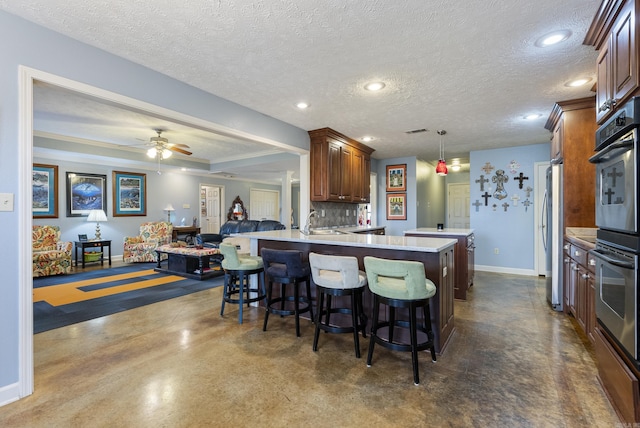 kitchen with kitchen peninsula, pendant lighting, a textured ceiling, and backsplash