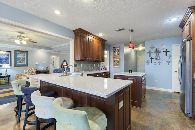 kitchen with hanging light fixtures, stainless steel fridge, a textured ceiling, tasteful backsplash, and kitchen peninsula