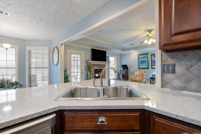 kitchen featuring a tile fireplace, sink, crown molding, a textured ceiling, and dishwashing machine