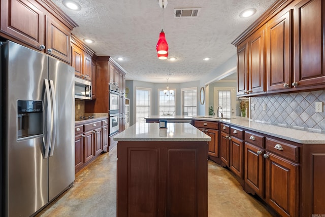 kitchen with kitchen peninsula, pendant lighting, stainless steel appliances, and sink