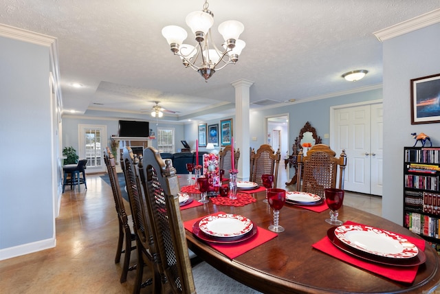 dining area featuring ceiling fan with notable chandelier, ornamental molding, a textured ceiling, a tray ceiling, and decorative columns