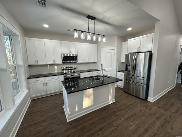 kitchen featuring white cabinets, appliances with stainless steel finishes, tasteful backsplash, and pendant lighting