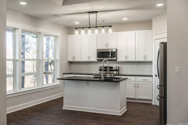 kitchen with white cabinetry, a kitchen island with sink, decorative light fixtures, and appliances with stainless steel finishes