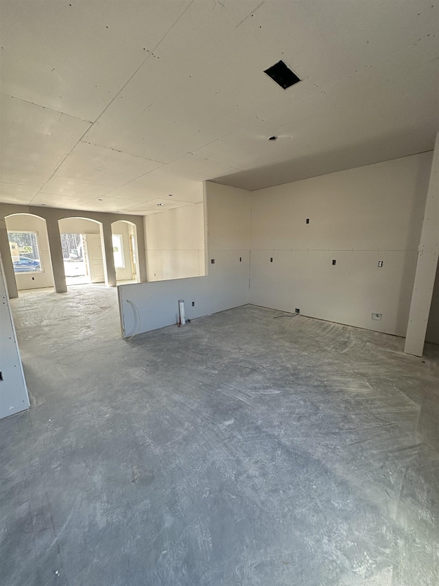 spare room with arched walkways and concrete floors