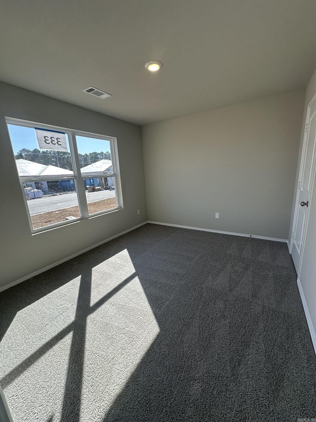 spare room with visible vents, baseboards, and dark carpet