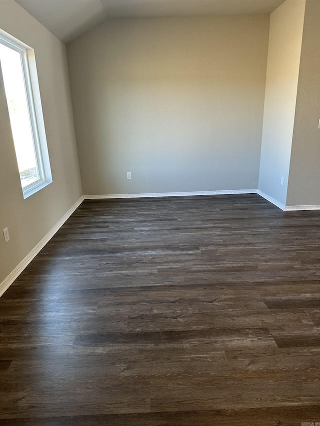 spare room with vaulted ceiling, baseboards, and dark wood-style flooring