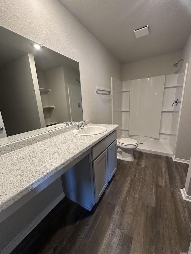 bathroom featuring vanity, toilet, wood finished floors, and walk in shower