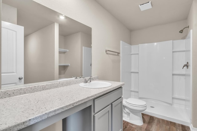 full bath with toilet, wood finished floors, vanity, and a walk in shower