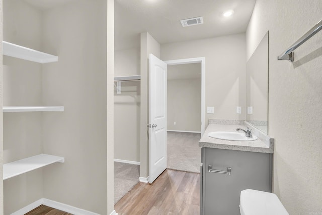 bathroom with visible vents, toilet, wood finished floors, baseboards, and vanity