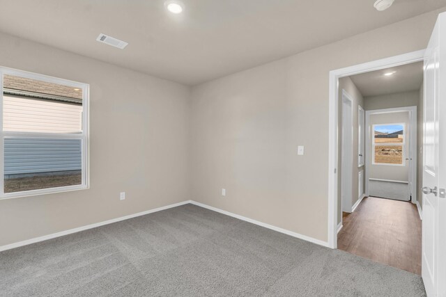 carpeted spare room with a wealth of natural light, visible vents, recessed lighting, and baseboards