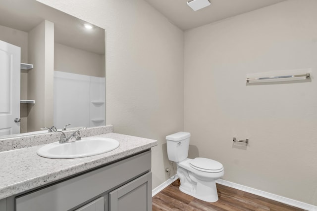 bathroom featuring toilet, wood finished floors, a shower, baseboards, and vanity