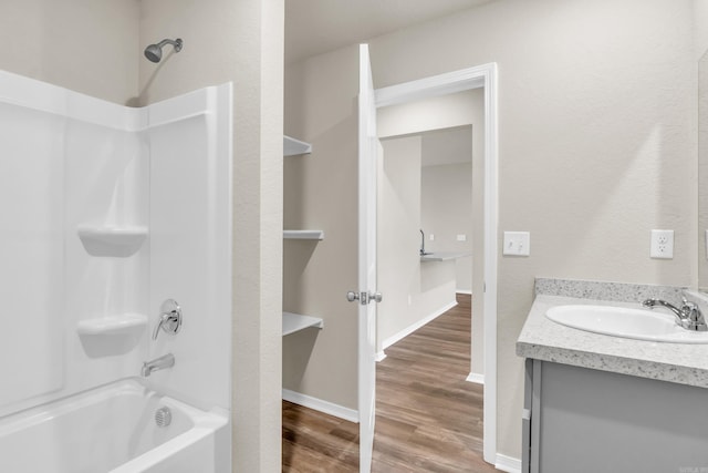 full bathroom featuring baseboards, wood finished floors, shower / washtub combination, and vanity