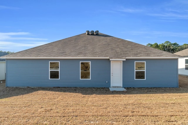 rear view of property featuring a yard and roof with shingles