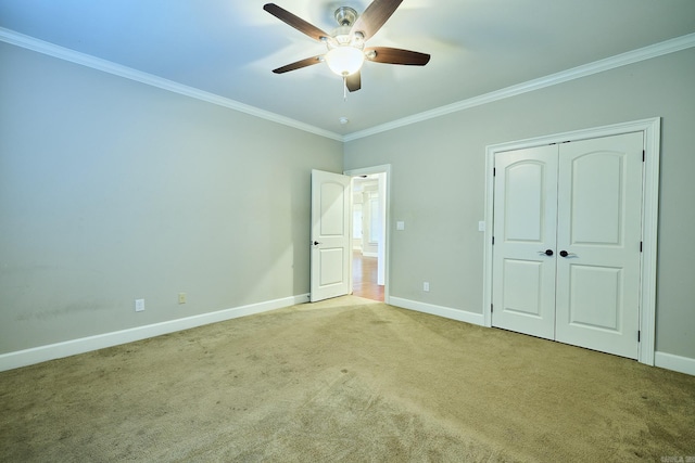 unfurnished bedroom featuring a closet, ceiling fan, crown molding, and light colored carpet