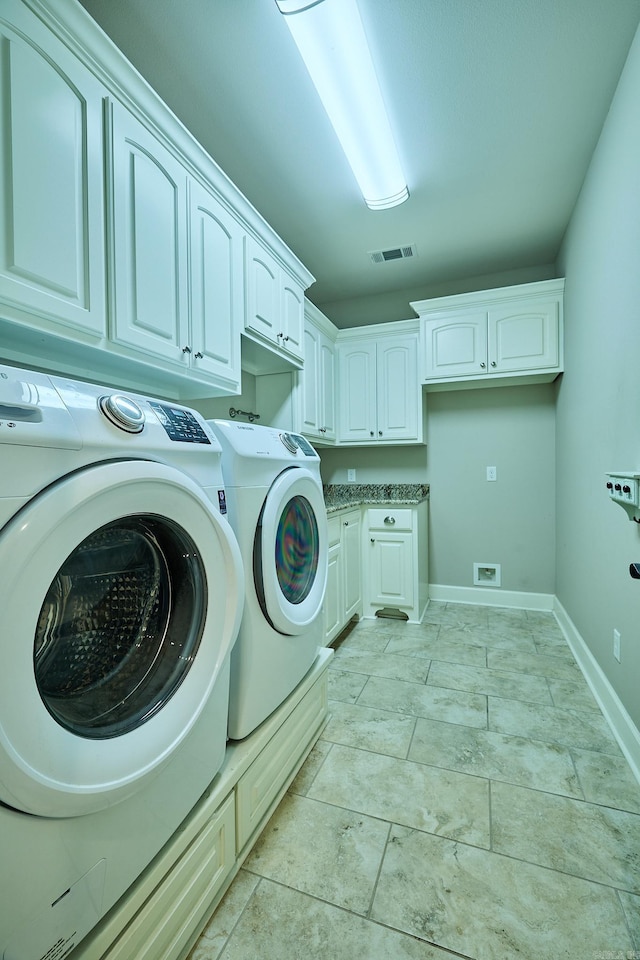 clothes washing area with cabinets and separate washer and dryer