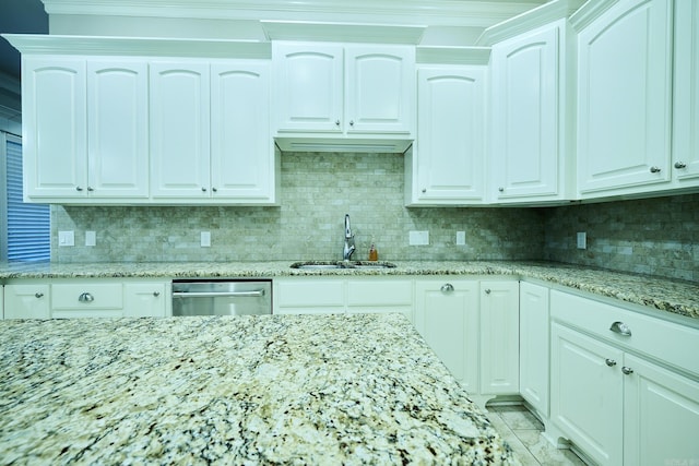 kitchen with decorative backsplash, white cabinetry, stainless steel dishwasher, and sink