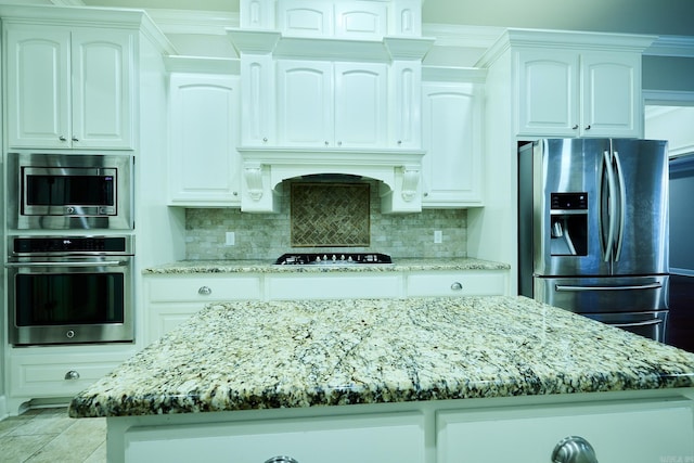 kitchen with backsplash, stainless steel appliances, white cabinetry, and a kitchen island