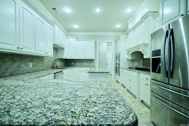 kitchen featuring light stone countertops, backsplash, stainless steel appliances, and white cabinetry