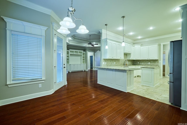 kitchen featuring ceiling fan with notable chandelier, hanging light fixtures, white cabinetry, light stone counters, and kitchen peninsula