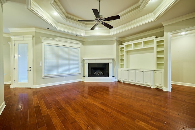 unfurnished living room featuring dark hardwood / wood-style floors, a raised ceiling, ceiling fan, and ornamental molding