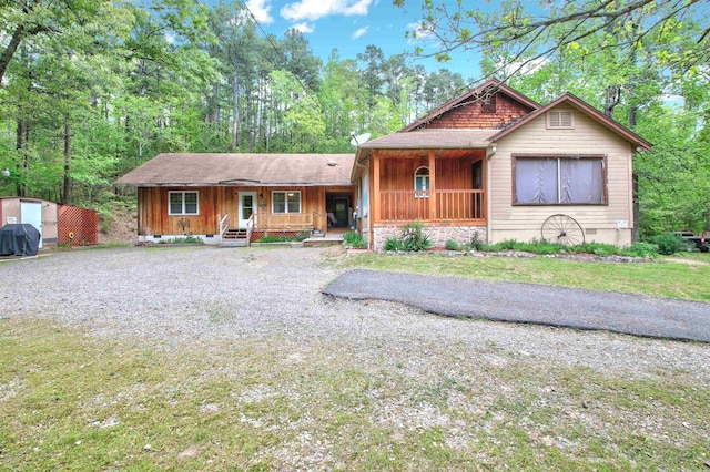 view of front of property featuring covered porch and a storage shed