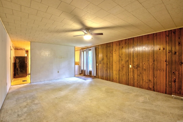 unfurnished room with carpet, ceiling fan, and wooden walls