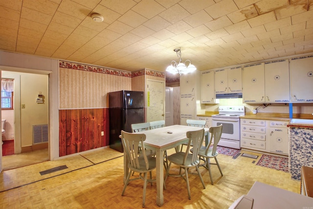 dining area featuring a notable chandelier and wood walls