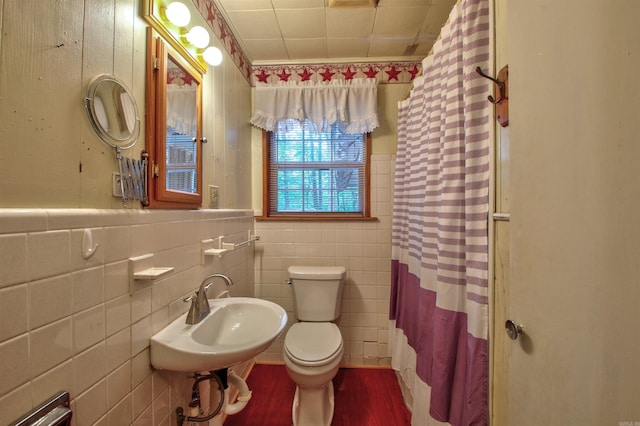 bathroom with sink, a shower with shower curtain, toilet, ornamental molding, and tile walls