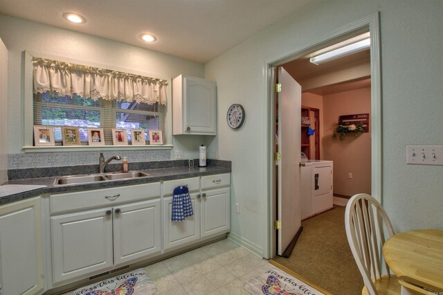 kitchen with independent washer and dryer, white cabinetry, and sink