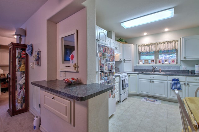 kitchen with sink, stainless steel range oven, kitchen peninsula, white fridge, and white cabinets