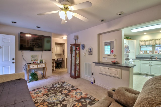 living room with ceiling fan, light colored carpet, and sink