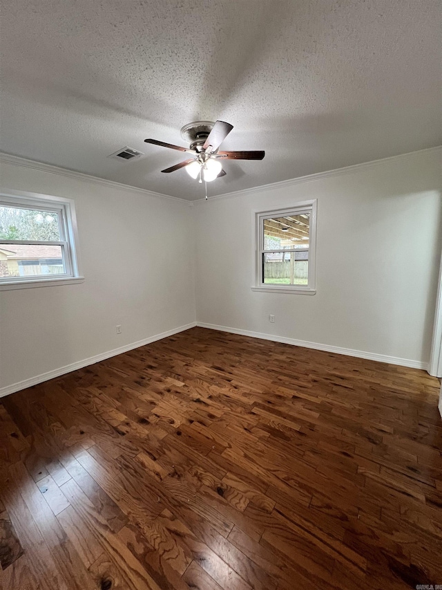 empty room featuring ornamental molding, a textured ceiling, and dark wood-type flooring