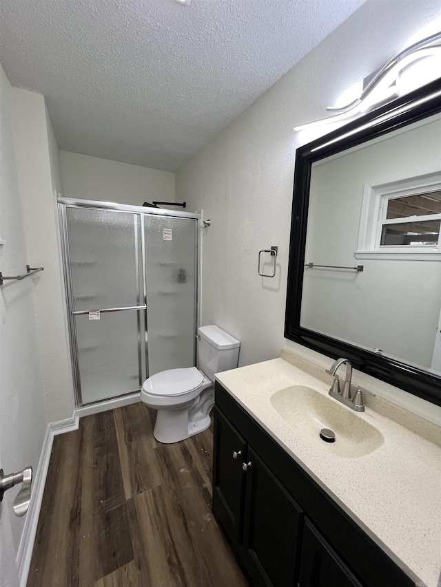 bathroom with hardwood / wood-style floors, vanity, toilet, a textured ceiling, and walk in shower