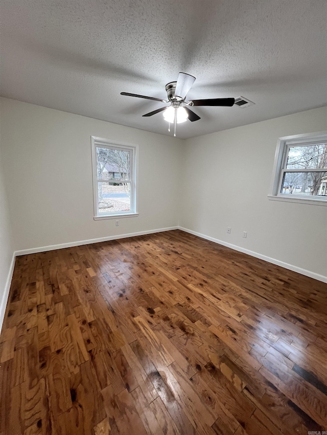 spare room with a textured ceiling, ceiling fan, and dark wood-type flooring